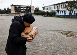 Харьковчанка целует буханку хлеба, полученную в рамках гуманитарной помощи