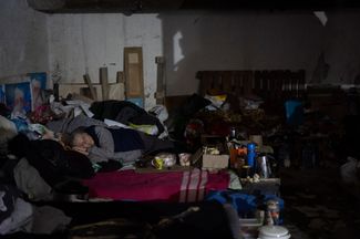Женщина лежит на кровати в подвале-бомбоубежище во время российских атак Луганской области