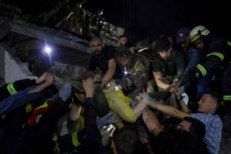 Спасатели и волонтеры выносят женщину из-под завалов