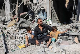 Палестинец со своими детьми на развалинах дома в Рафахе. 12 октября 2023 года