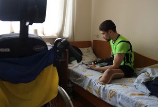 23-летний Роман, который потерял обе ноги и правую руку ниже локтя в боях на юго-востоке Украины, надевает протез руки в своей палате в реабилитационном центре