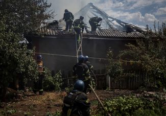 Пожарные тушат один из пострадавших от обстрела домов, 9 июля 2022 года