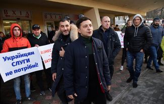 Volodymyr Zelenskiy stands in front of demonstrators protesting his candidacy before a performance in Lviv. February 8, 2019