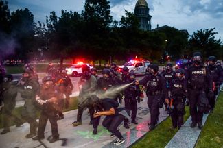 Полицейские поливают демонстрантов перечным спреем во время протестов против убийства Джорджа Флойда. Денвер, штат Колорадо, 30 мая 2020 года