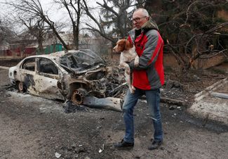Житель Донецка выносит собаку из дома, который попал под обстрел украинской стороной 28 февраля 2022 года