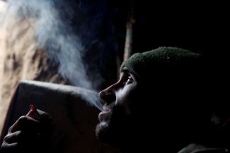 Украинский солдат курит в укрытии во время обстрела