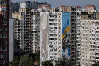 Мурал с изображением украинского военнослужащего, который держит кота, на одном из многоэтажных домов в Киеве