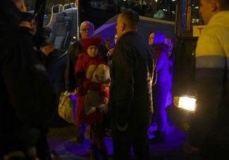 Беженцы высаживаются из автобуса на железнодорожной станции