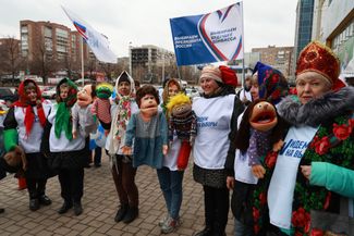Женщины в платках и кокошниках призывают принять участие в выборах президента России на одной из улиц Донецка. На баннере, который они держат, написано: «Выбираем президента России, выбираем будущее Донбасса»