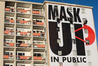 Плакат с призывом носить маски в общественных местах на стене жилого дома в Кейптауне, 16 мая 2020 года