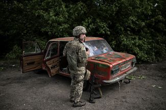 Украинский военный возле разбитого автомобиля «Жигули» под Лисичанском