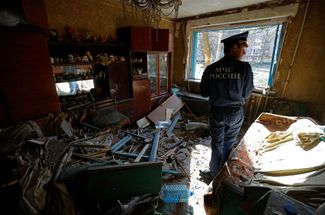 Сотрудник МЧС России осматривает одну из квартир, пострадавшую во время обстрела