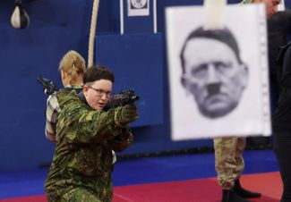 Участница женского движения клуба «Ярополк» тренируется в стрельбе на портрете Гитлера. 3 декабря 2022 года