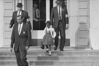 Судебные приставы сопровождают шестилетнюю Руби Бриджес. Она стала первой чернокожей ученицей школы в Новом Орлеане после отмены расовой сегрегации в учебных заведениях штата. В знак протеста родители белых учеников стали забирать своих детей из школы. Новый Орлеан, штат Луизиана, 1 ноября 1960 года