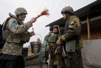 Недалеко от линии фронта в Харьковской области капеллан благословляет солдат в канун православной Пасхи