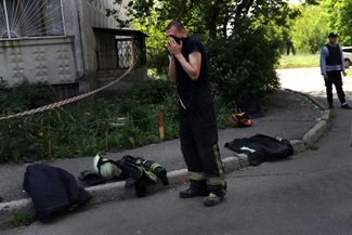 Спасатель в Харькове делает передышку во время работы в обстрелянном жилом доме, где остаются тела погибших мирных жителей
