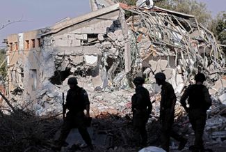 Израильские солдаты в кибуце Беэри у разрушенного дома. 14 октября 2023 года