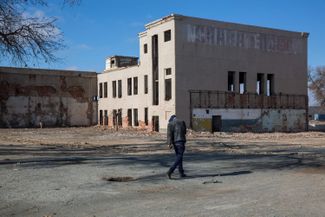 A pedestrian walks past an abandoned fish canning factory in Moynaq, Uzbekistan, on Wednesday, March 14, 2018. The drying up of the Aral Sea led to the economic demise of Moynaq, once a busy Soviet fishing port. 