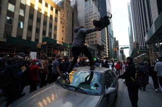 Участник протестов запрыгивает на крышу машины. Нью-Йорк, 1 июня 2020 года