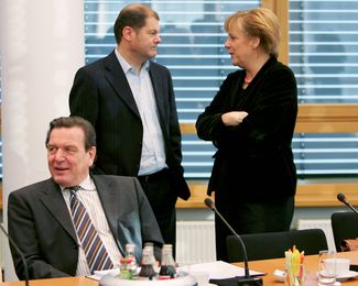 Герхард Шредер (сидит), Олаф Шольц и Ангела Меркель в 2005 году, когда Меркель сменила Шредера на посту канцлера, после чего Шольц в очередной раз исчез из большой политики.