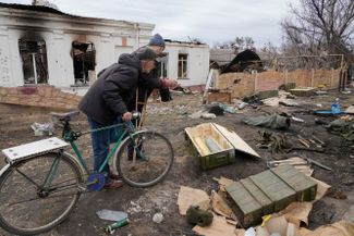 Жители Тростянца рассматривают нерасстрелянные артиллерийские снаряды, оставшиеся после битвы, в ходе которой украинские войска освободили город от российских. 28 марта 2022 года<br>