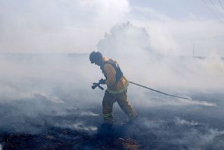 Израильский пожарный борется с возгоранием на границе с Газой, вызванным ракетными ударами боевиков ХАМАС, 16 мая 2021
