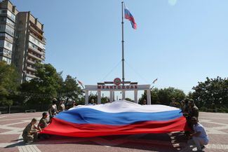 Российские военные разворачивают триколор на площади в оккупированном Мелитополе Запорожской области