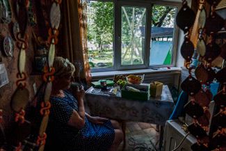 Жительница города курит на кухне у разбитых авиаударом окон
