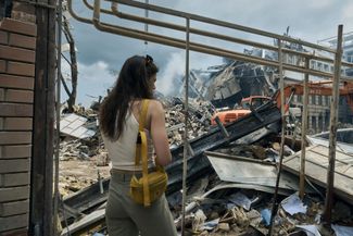 Жительница Одессы наблюдает за работой спасателей на месте одного из разрушенных зданий