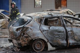 An emergency worker near a burned car