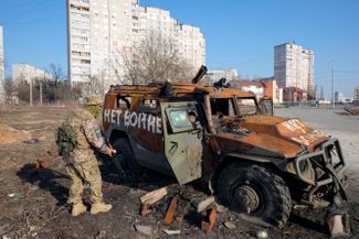 Украинский солдат осматривает подбитый российский бронетранспортер в Харькове