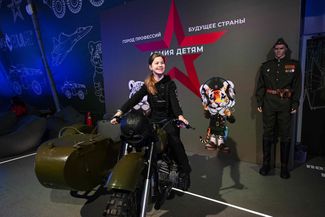 A visitor of the Rossiya exhibition poses on a retro motorcycle in the Russian Defense Ministry’s pavilion at the All-Russian Exhibition Center