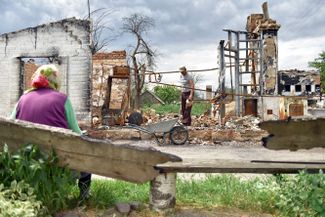 Житель села Новоселовка убирает обломки своего живого дома, разрушенного в марте в результате обстрела со стороны России. Сейчас его мать живет в теплице