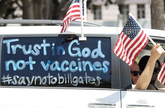 «Верь в Бога, а не в прививки #нетбиллугейтсу»: плакат на митинге за снятие карантина. Лос-Анджелес, штат Калифорния, 22 апреля 2020 года