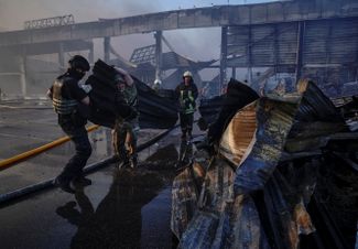 Спасатели и военнослужащие работают на месте торгового центра, по которому нанесли удар российские войска