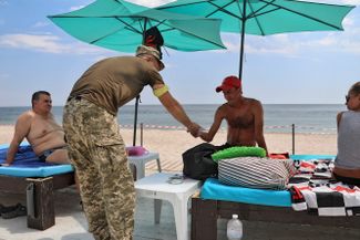 Мужчина подписывает повестку о явке в военкомат на пляже Одессы