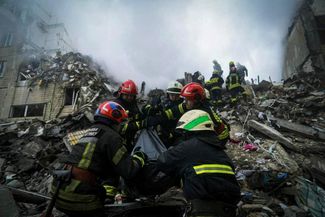 Спасатели выносят тело жителя, погибшего в результате попадания в дом ракеты