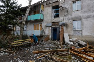 72-летняя Екатерина забирает оставшиеся вещи из своей разрушенной квартиры в Луганском