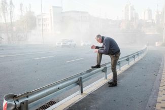 Житель Киева отряхивает брюки от пыли, поднявшейся от взрыва