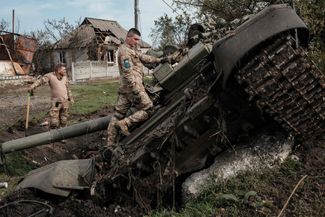Украинские солдаты обследуют брошенный российский танк в недавно освобожденном селе Кирилловка Харьковской области