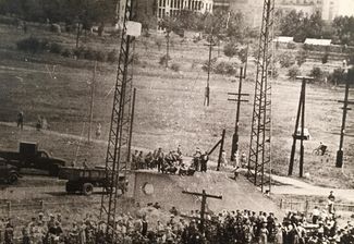 The first day of protests: workers block the railway and hang from an electrical tower a banner reading, “Meat, butter, and higher pay!” June 1, 1962. Image displayed at the Novocherkassk Memorial Museum.