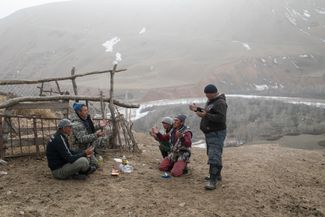 Murat and his crew of prospectors pray while waiting for a gold buyer in the village of Eki-Naryn after work. The Kichi-Naryn River can be seen behind them.