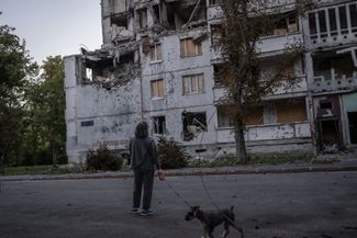 Женщина гуляет с собакой около разрушенного здания