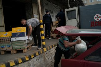 Волонтеры загружают машину едой в центре распределения пожертвований в Северодонецке