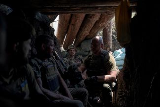 Украинские солдаты сидят в недавно захваченном российском окопе на передовой под Бахмутом
