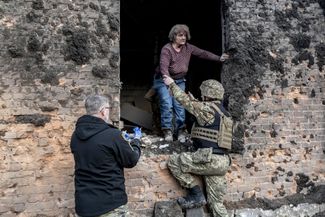 Украинские военные помогают раненой жительнице Константиновки выбраться из здания, в которое попала российская ракета