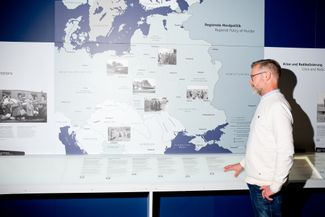 Eike Stegen stands next to an educational display in the Wannsee House’s memorial center