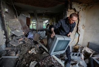 Жители Донецка на фоне разрушенного ракетным ударом жилого дома