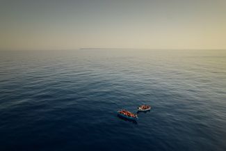 Группа людей (предположительно, мигрантов из Туниса) на борту деревянной лодки ожидает помощи от членов испанской неправительственной организации Open Arms недалеко от итальянского острова Лампедуза. 29 июля