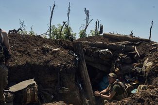 Украинский солдат сидит в захваченном российском окопе на линии фронта возле Бахмута. 4 июля 2023 года
